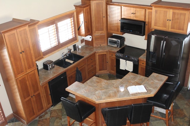 kitchen with sink, black appliances, and a kitchen bar