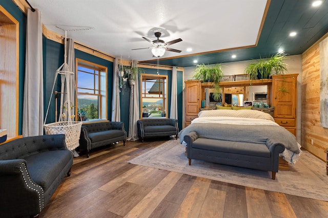 bedroom with wooden walls, dark hardwood / wood-style floors, and ceiling fan