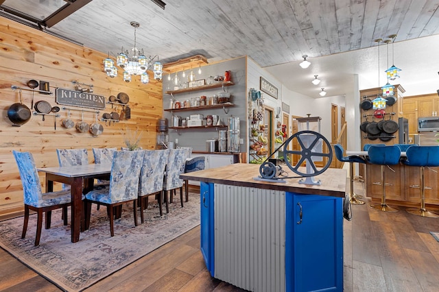 kitchen with a center island, blue cabinetry, a notable chandelier, wood walls, and a kitchen bar