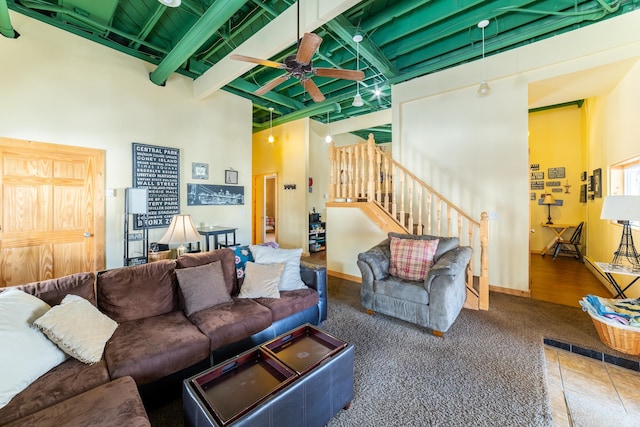 living room featuring ceiling fan, a high ceiling, and beamed ceiling