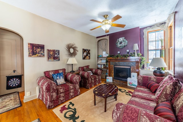 living room with light hardwood / wood-style flooring, ceiling fan, and a high end fireplace