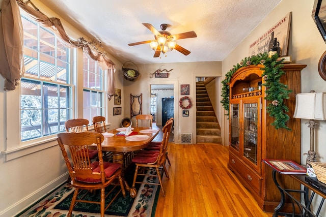 dining space with a textured ceiling, ceiling fan, and light hardwood / wood-style flooring