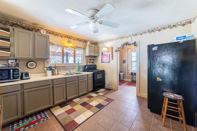 kitchen featuring light tile floors, black appliances, gray cabinetry, ceiling fan, and a textured ceiling