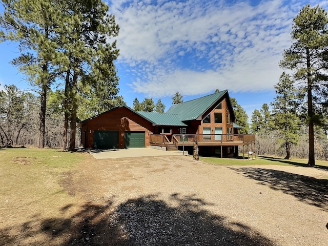 back of house with a deck, an outdoor structure, a garage, and a lawn