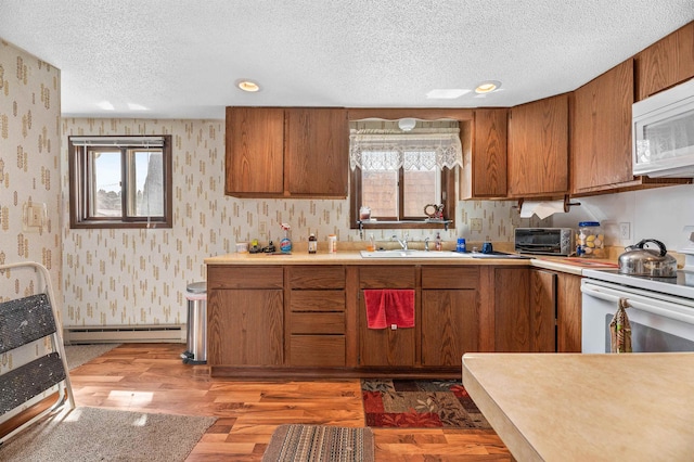 kitchen featuring white appliances, a textured ceiling, dark wood-type flooring, baseboard heating, and sink