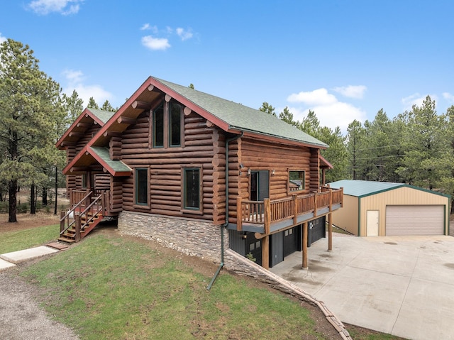 log cabin featuring a front yard, a garage, a wooden deck, and an outbuilding