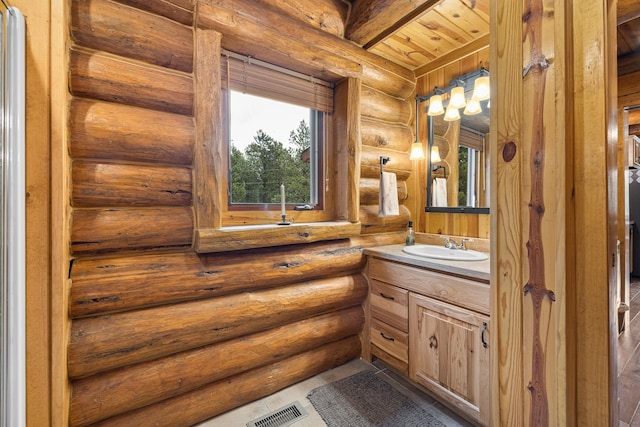 bathroom featuring log walls, beam ceiling, tile patterned floors, wooden ceiling, and vanity