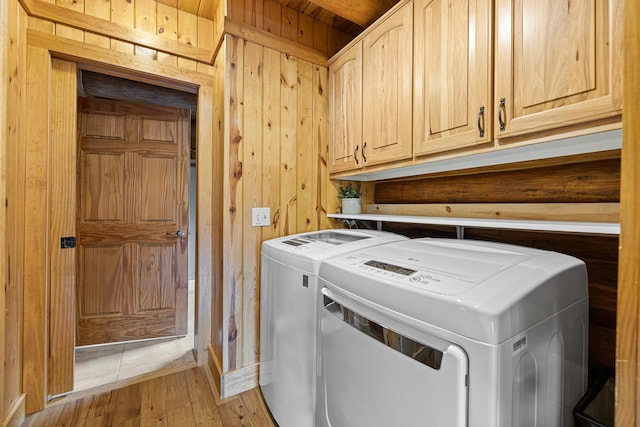 laundry area featuring cabinets, washer and clothes dryer, wooden walls, and wood-type flooring