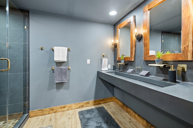 bathroom with hardwood / wood-style flooring, an enclosed shower, tasteful backsplash, and sink