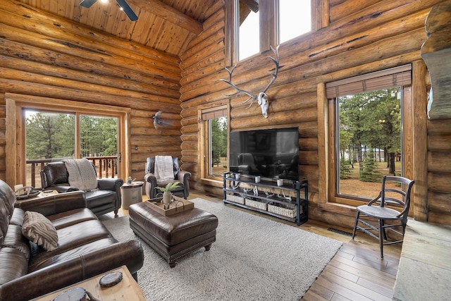 living room with hardwood / wood-style flooring, a wealth of natural light, log walls, wood ceiling, and beamed ceiling