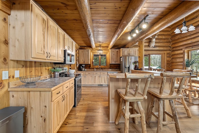 kitchen featuring appliances with stainless steel finishes, light brown cabinets, rustic walls, light hardwood / wood-style flooring, and beam ceiling