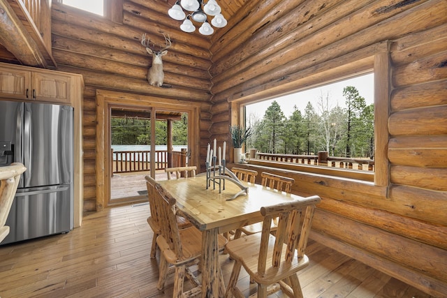 dining space with rustic walls, a chandelier, and light hardwood / wood-style floors