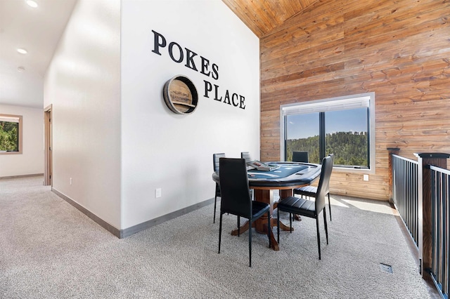 carpeted dining area featuring wood ceiling, high vaulted ceiling, and wooden walls