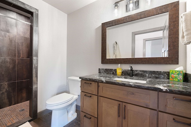 bathroom featuring oversized vanity, toilet, and a tile shower