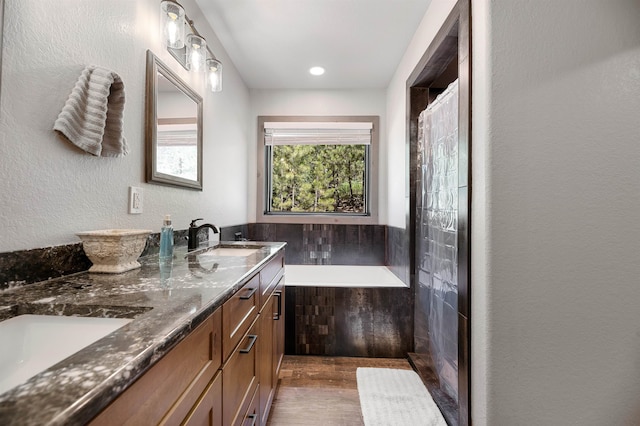 bathroom with tile walls, double vanity, and a bathtub