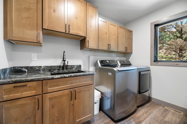 laundry room featuring hardwood / wood-style flooring, cabinets, sink, and washer and dryer