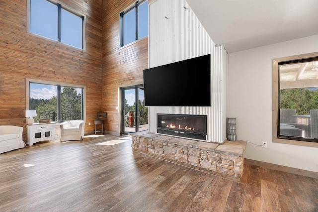 unfurnished living room featuring wood-type flooring, a fireplace, wood walls, and a towering ceiling