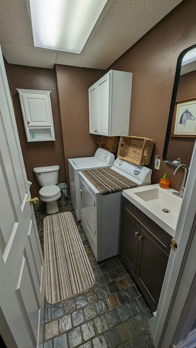 laundry area with sink, dark tile flooring, and separate washer and dryer