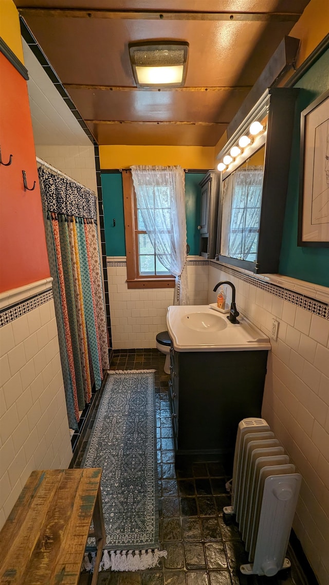 bathroom featuring radiator, tile walls, tile floors, and large vanity