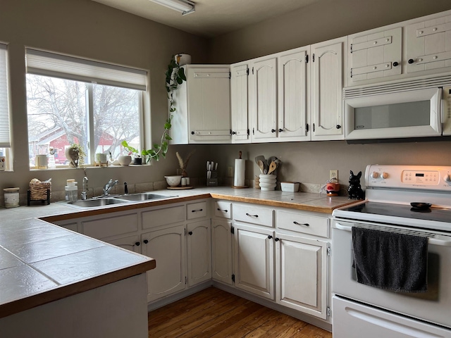 kitchen with white cabinets, white appliances, dark hardwood / wood-style floors, sink, and tile countertops