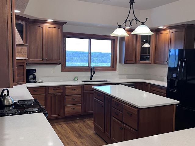 kitchen with a sink, light countertops, black appliances, and dark wood-style floors