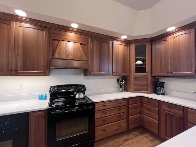 kitchen featuring light countertops, wall oven, black / electric stove, custom exhaust hood, and glass insert cabinets