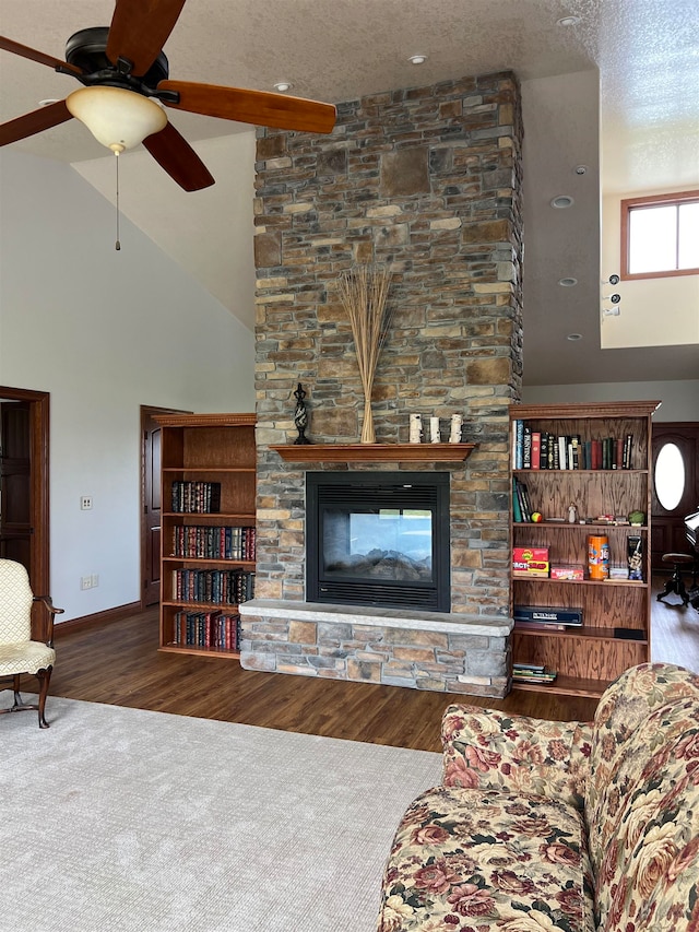 living room with wood-type flooring, ceiling fan, a fireplace, and a textured ceiling