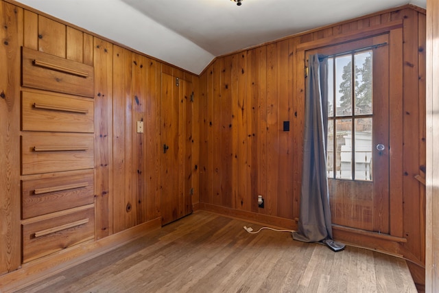 unfurnished room featuring wood walls, hardwood / wood-style floors, and lofted ceiling