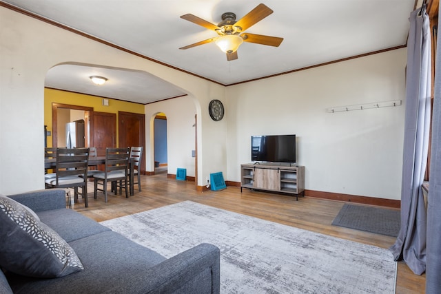 living room with ornamental molding, wood-type flooring, and ceiling fan