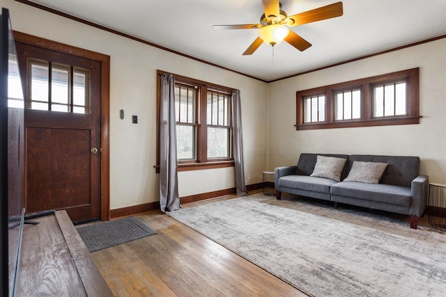 living room featuring a healthy amount of sunlight, wood-type flooring, ceiling fan, and crown molding