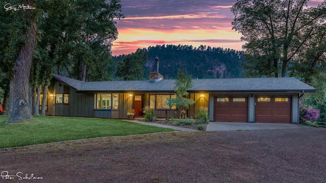 view of front of home with driveway, board and batten siding, an attached garage, a front yard, and covered porch