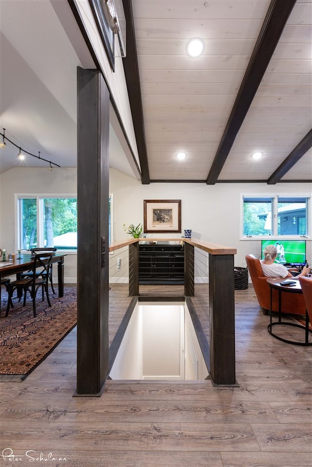 kitchen featuring kitchen peninsula, wood-type flooring, and vaulted ceiling with beams