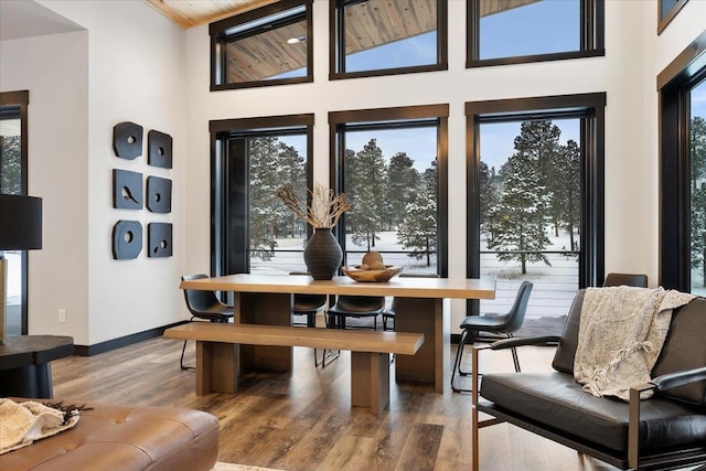 dining area featuring a towering ceiling, baseboards, and wood finished floors