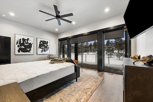 bedroom with multiple windows, recessed lighting, wood finished floors, and access to exterior