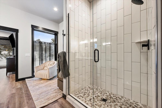 bathroom with a stall shower, baseboards, and wood finished floors