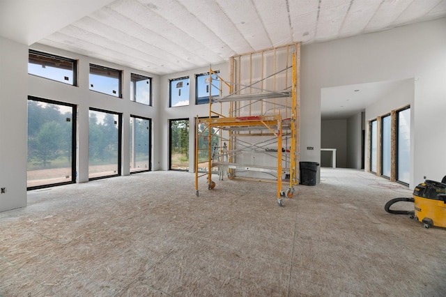 unfurnished living room featuring a healthy amount of sunlight and a high ceiling