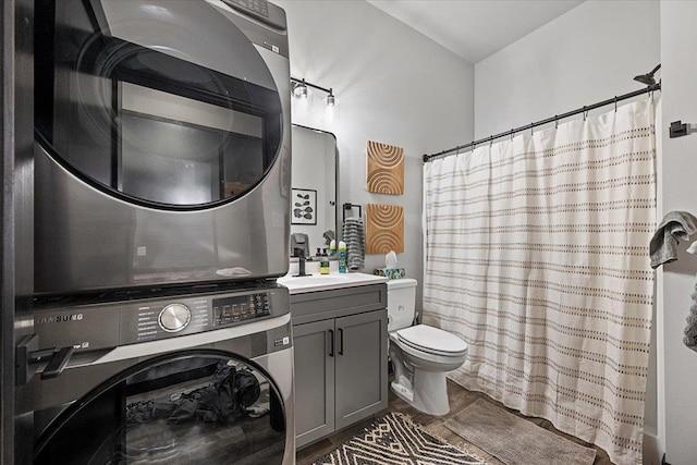 bathroom featuring toilet, a shower with shower curtain, vanity, and stacked washer and clothes dryer