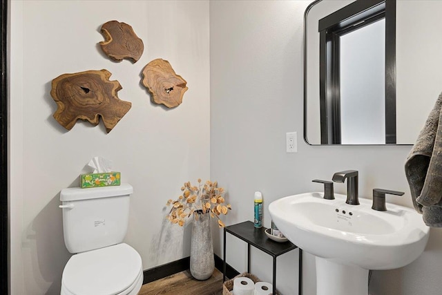 half bathroom with toilet, a sink, and wood finished floors