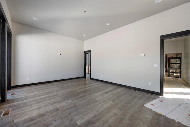 empty room featuring baseboards, visible vents, and wood finished floors