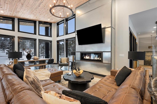 living room featuring recessed lighting, a high ceiling, a glass covered fireplace, wood ceiling, and a chandelier