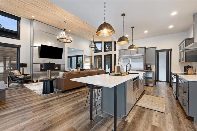 kitchen featuring light countertops, gray cabinets, dark wood-style flooring, and built in appliances