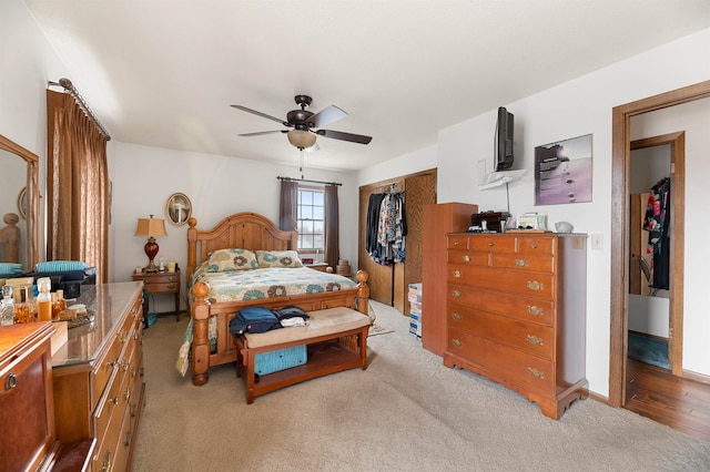 bedroom with light colored carpet, ceiling fan, and a closet