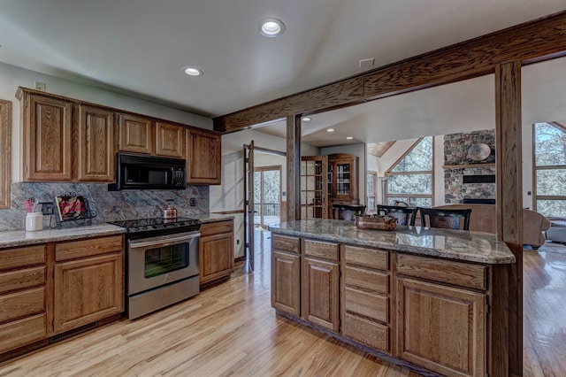 kitchen with stone counters, tasteful backsplash, light wood-type flooring, and stainless steel electric stove