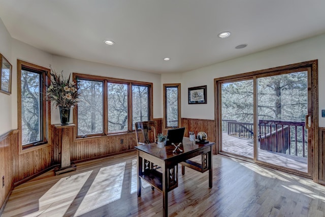 dining space featuring plenty of natural light, wooden walls, and light wood-type flooring