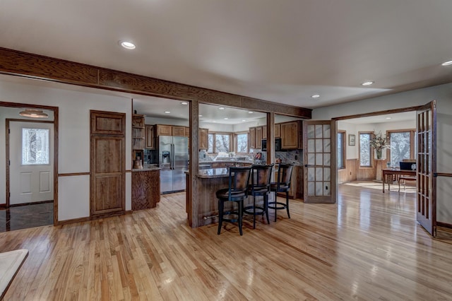 interior space with a wealth of natural light, light hardwood / wood-style flooring, stainless steel refrigerator with ice dispenser, and black microwave