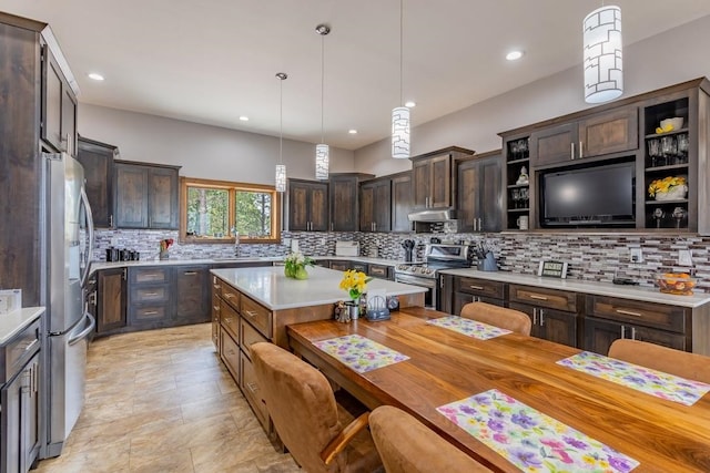 kitchen featuring dark brown cabinets, stainless steel appliances, decorative light fixtures, backsplash, and sink