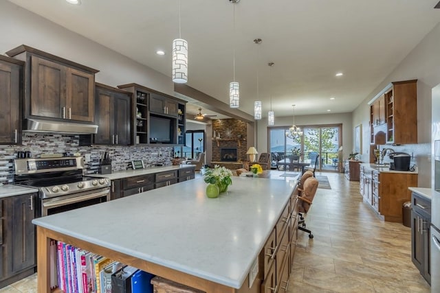 kitchen featuring stainless steel electric range, backsplash, hanging light fixtures, a large island, and a breakfast bar