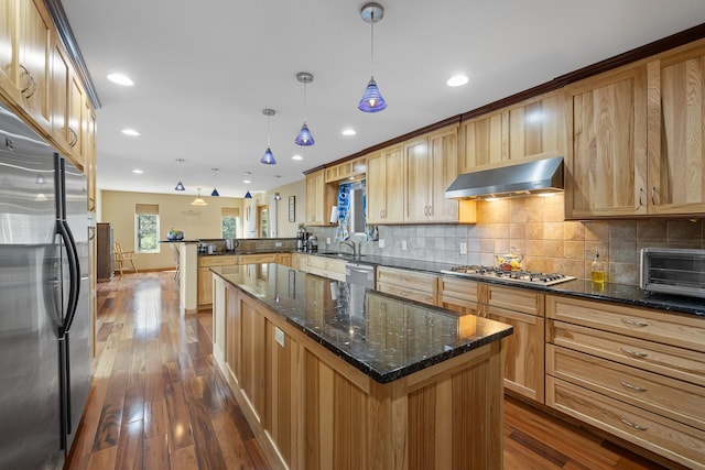 kitchen with backsplash, appliances with stainless steel finishes, a center island, and dark hardwood / wood-style floors