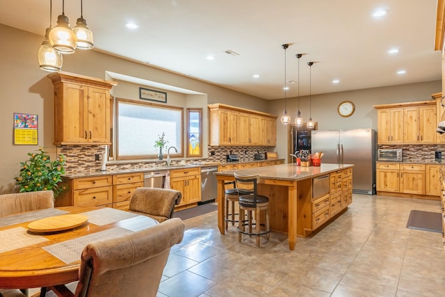 kitchen featuring a center island, stainless steel appliances, tasteful backsplash, and light stone countertops