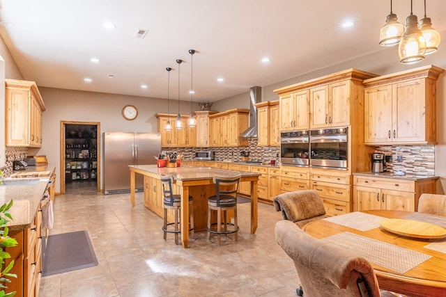 kitchen with stainless steel appliances, wall chimney range hood, a center island, and tasteful backsplash